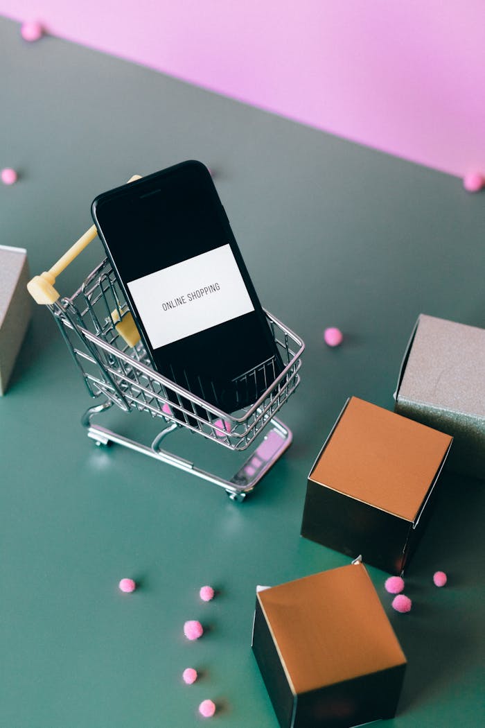 Conceptual image of online shopping with a smartphone in a miniature cart.